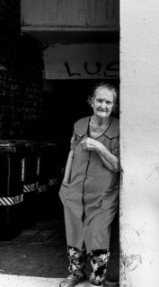 Black and white photography, street art, senior woman standing in front of the front door, Lisbon,