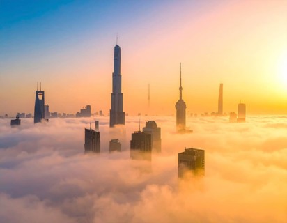 City scape emerging from a dense enveloping fog in sunrise and skyscrapers piercing the haze, big