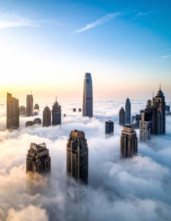 City scape emerging from a dense enveloping fog in sunrise and skyscrapers piercing the haze, big