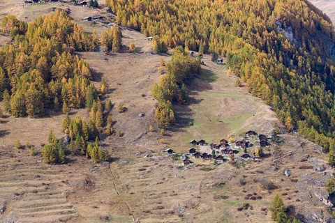 Tiny little town on the mountain. Wooden nostalgic houses are surrounded by grassland and forest in