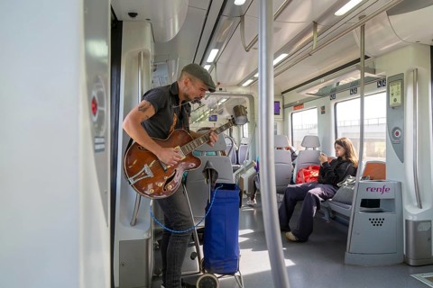 Musician busker playing guitar onboard train of Rodalia de Barcelona suburban rail network,
