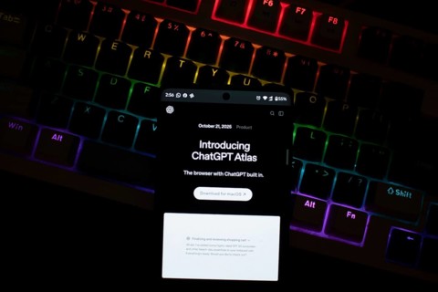 Smartphone with ChatGPT Atlas text in front of a backlit keyboard