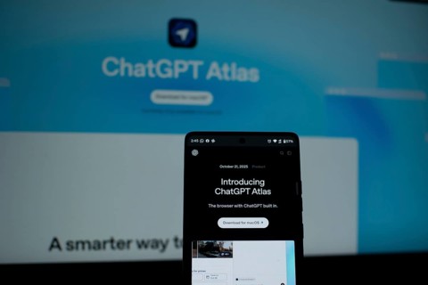 A smartphone highlighting ChatGPT Atlas in front of a blue screen
