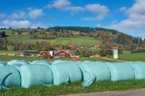 Blue sky with clouds, silage bales in front of the village of Masers under the mountain Blender
