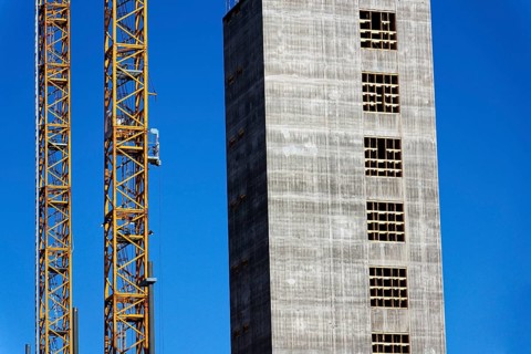 Two yellow cranes on skyscraper construction site of timber building Kaj 16 with hybrid concrete