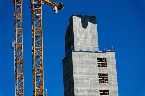 Yellow cranes on construction site of timber building Kaj 16 with hybrid concrete frames, sunny