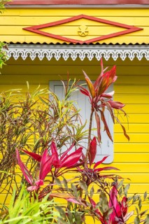 Typical Creole architecture of a house with a yellow wooden façade, white lambrequin over a window