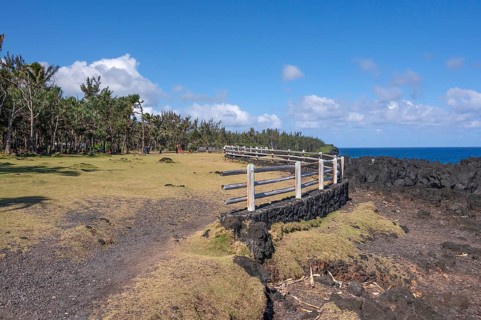 A rustic wooden barrier on a black lava foundation borders the viewpoint at Cap Mechant, where the