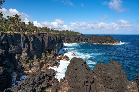 Massive, black lava cliffs rise steeply out of the Indian Ocean at Cap Mechant, where white surf