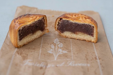 Close-up of a mooncake (mooncake) cut in the middle with a thick layer of dark red bean paste and a