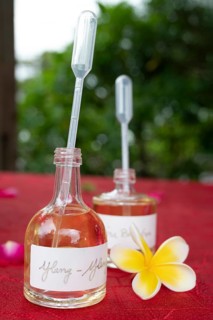 Two small, transparent glass bottles with a pipette-shaped cap contain amber-colored essential oil