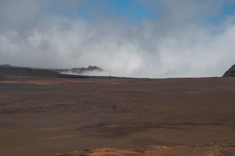 The Route du Volcan leads through the vast, rust-red lunar landscape of the Plaine des Sables,
