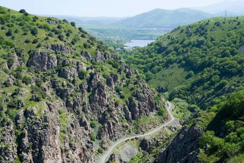 A green mountain landscape with rocks crossed by a road with a wide view of the valley, canyon of