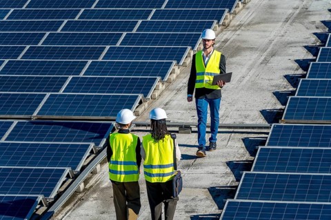 Engineers checking a large installation of solar panels on a commercial rooftop, ensuring optimal