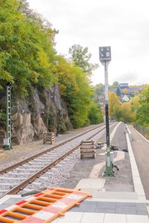 Railway tracks next to rocky embankment and trees, autumn landscape, signal building on the Hermann