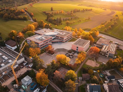 Modern Maria von Linden Gymnasium school building in autumn landscape at sunset, captured by drone,