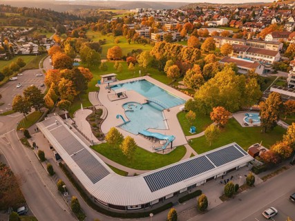 Aerial view of an outdoor pool surrounded by trees and residential area in autumn, Calw, Black
