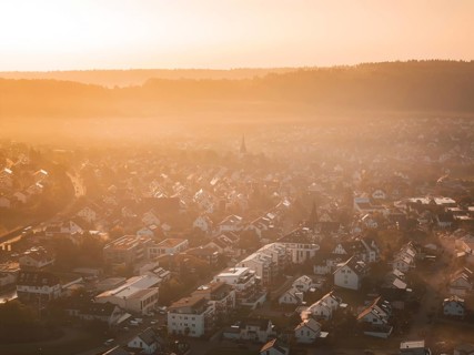 Aerial view of a village in morning fog at sunrise with warm orange light, Calw Stammheim, Black
