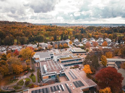 School building surrounded from above by autumn-colored trees and thick forest, Sindelfingen,