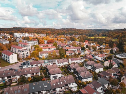 Residential area with terraced houses and surrounding colorful autumn trees in slightly cloudy