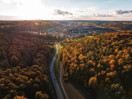 Autumn forest landscape with a road leading to a small settlement, Aidlingen, Böblingen district,
