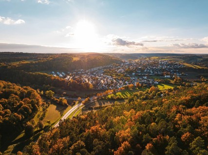Colourful autumn landscape with a view of a village and vast forests under the evening sun,