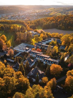 Sunlight illuminates motherhouse buildings and autumn trees in rural surroundings, Aidlingen,