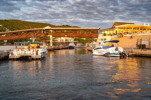 Several boats and catamarans are moored on the jetty in the port of Saint-Gilles, whose water