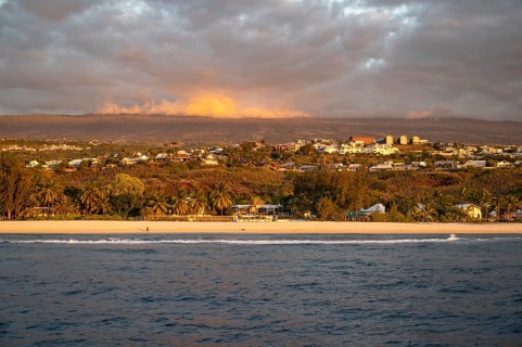 The bright sandy beach of the Saint-Gilles lagoon with bathers merges into a coastal landscape with