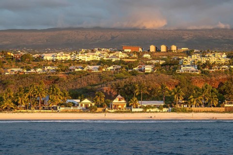 The bright sandy beach of the Saint-Gilles lagoon with bathers merges into a coastal landscape with