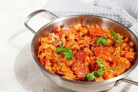 Polish dish bigos, in a stainless steel pan, stewed meat with cabbage, chorizo sausages, mushrooms,