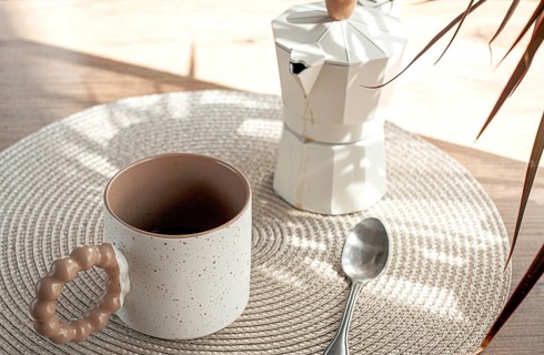 Making morning coffee, geyser coffee maker and mug, in bed colors, on a wooden table, natural