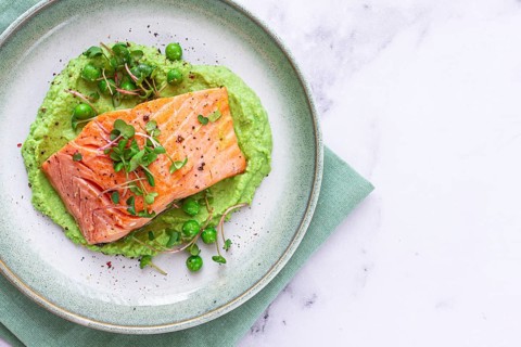 Delicious grilled salmon is placed elegantly on creamy green pea puree. Fresh microgreens and peas