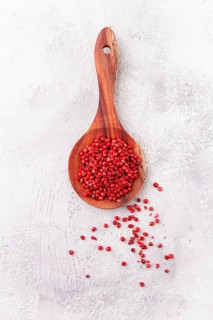 Wooden spoon with red peppercorns, on a light background, top view