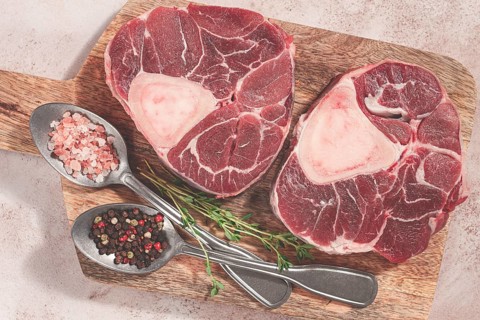 Knuckle on the bone, raw ossobuco meat, on a wooden chopping board, with spices, top view, no