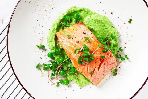 Delicious grilled salmon is placed elegantly on creamy green pea puree. Fresh microgreens and peas