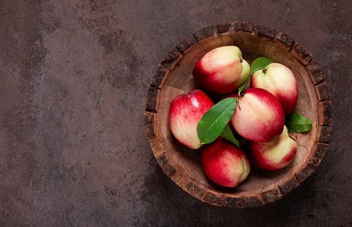 Ripe nectarine, in a wooden plate, brown background, top view, no people