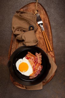 Fried egg with bacon, in a cast-iron pan, breakfast, top view, close-up, homemade, no people