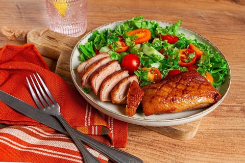 Delicious grilled duck breast served with fresh garden salad and cherry tomatoes at a rustic dining