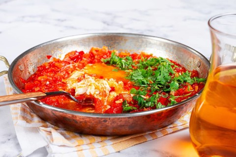 Traditional Turkish dish, scrambled eggs with tomatoes, Menemen, with herbs, in a frying pan,