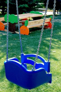 A bright blue swing hangs from sturdy chains in a lively playground. The well-maintained area