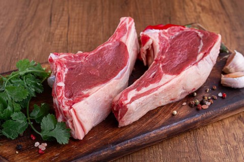 Freshly sliced lamb chops, with herbs and vegetables, on a wooden board, ready to cook, on a wooden