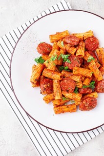 Rigatoni pasta with spicy sausage, and rich tomato sauce served, on a white plate, homemade