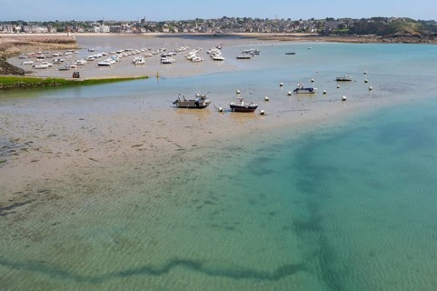 View of shallow turquoise water and moist sandy soil at low tide (low tide), with shadows of