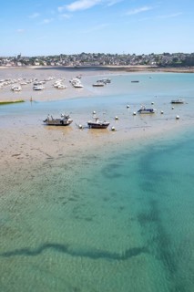 Over the shallow, turquoise water and moist sandy soil at low tide (low tide), with the shadows of