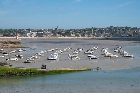 At low tide (low tide), a large collection of small motorboats lies neatly in rows on the moist