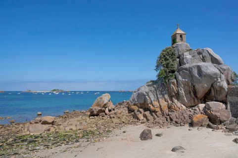 The small, historic Saint-Gildas chapel is perched on rugged, pink rock formations on the banks of