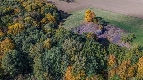 The scene shows an autumnal landscape with colorful foliage. An extinct volcano is surrounded by