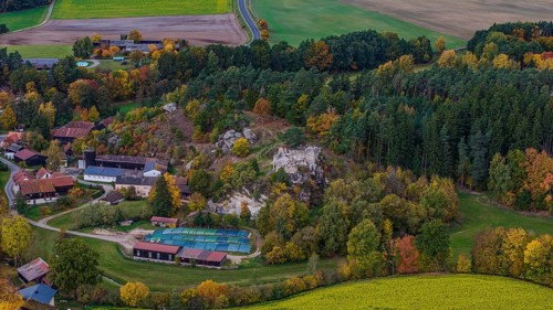 A picturesque village is surrounded by colorful trees in autumn. A castle ruin is nearby, while the