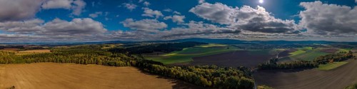 A breathtaking landscape with vast fields and deep blue skies. Sunlight shines onto the green area.